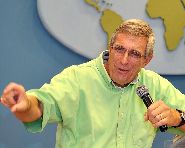 Darrow Miller teaching, holding a microphone